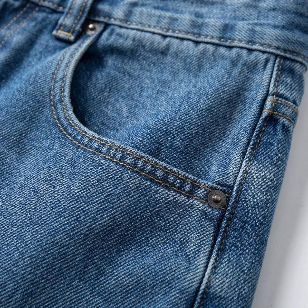 Close-up of the front pocket with contrast stitching and a metal rivet on the denim fabric
