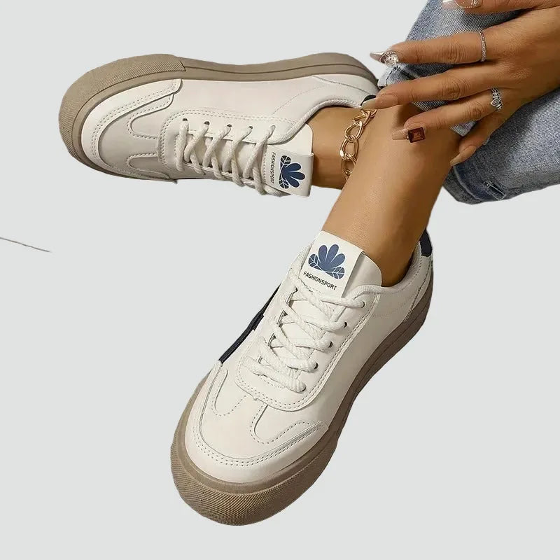 Cream leather trainers with lace-up front and tan platform sole, worn by a model with an ankle chain