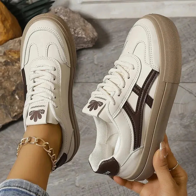 Rear view of white trainers with navy heel panels and tan platform soles worn with rolled-up jeans