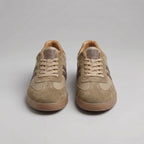 Close detail of the brown trainer's stitched stripes, suede trim and ridged gum outsole