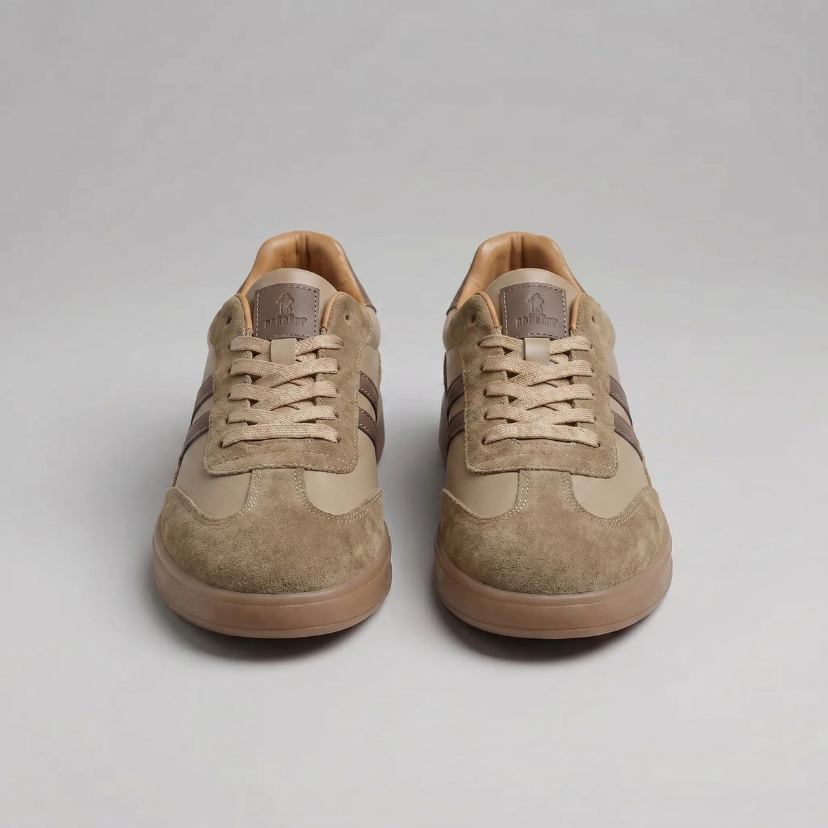 Close detail of the brown trainer's stitched stripes, suede trim and ridged gum outsole