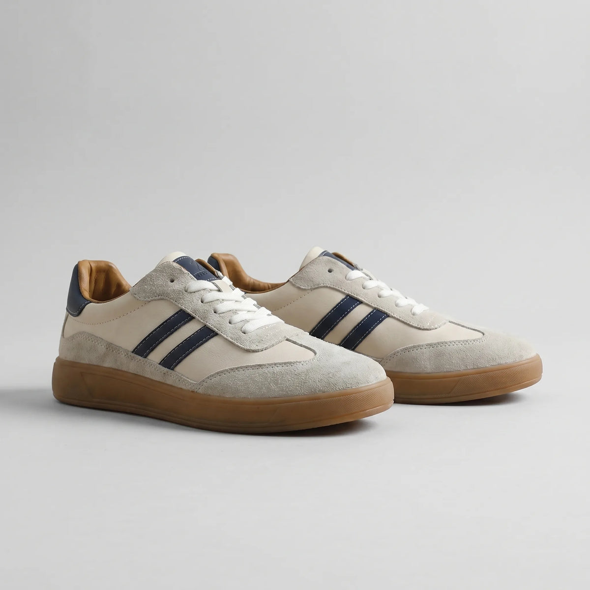 Side-by-side pair of off-white retro trainers showing navy leather stripes and tan suede panels