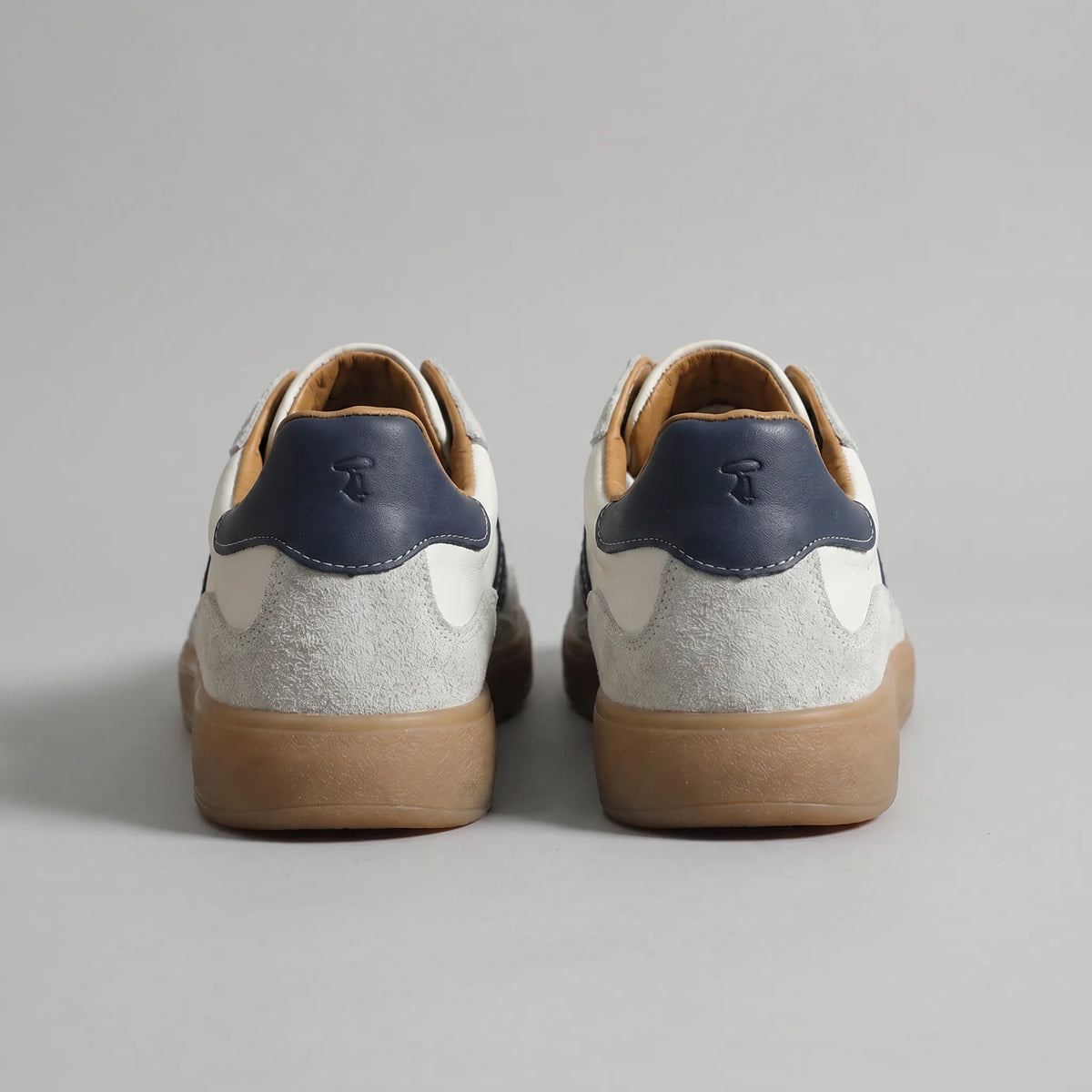Back view of both trainers showing navy heel tabs with embossed logo and grey suede heel counters