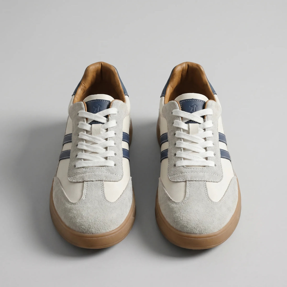 Front-on view of both trainers highlighting the crossed white laces and navy tongue trim