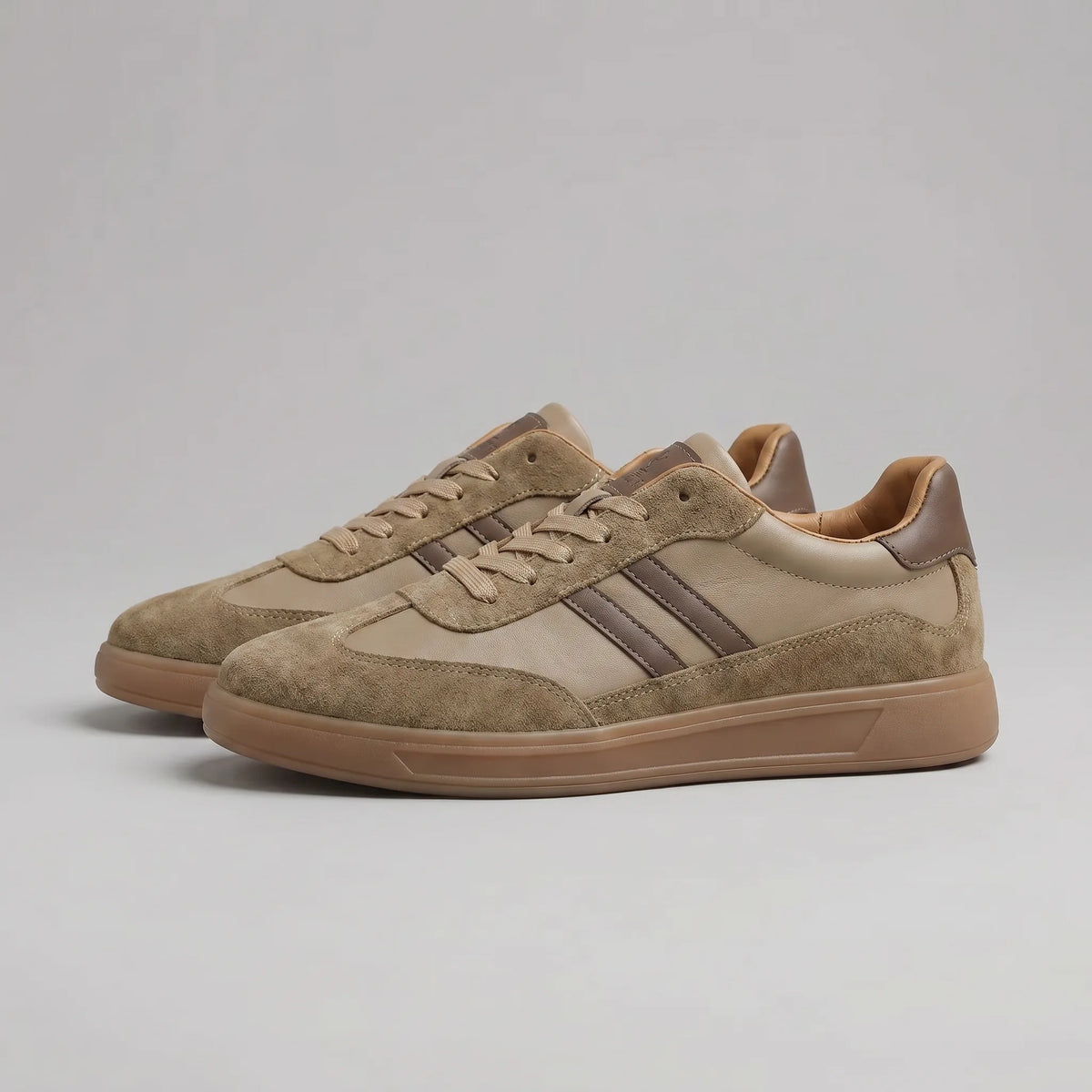 Angled view of brown suede and leather trainers showing the gum sole and tan leather lining