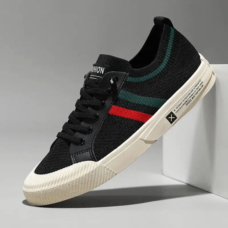 Side angle of black knit sneaker with green and red stripe detail and cream outsole