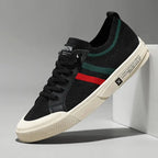 Side angle of black knit sneaker with green and red stripe detail and cream outsole
