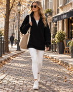 Black ribbed half-zip jumper layered over a white top, paired with white leggings and white trainers for a street style look