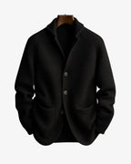 Black ribbed knit cardigan with notch lapel, three-button placket and patch pockets on a hanger