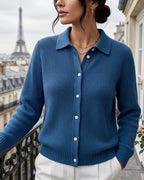 Front view of a steel blue ribbed knit cardigan with collar and button placket, hand resting on wrought iron railing