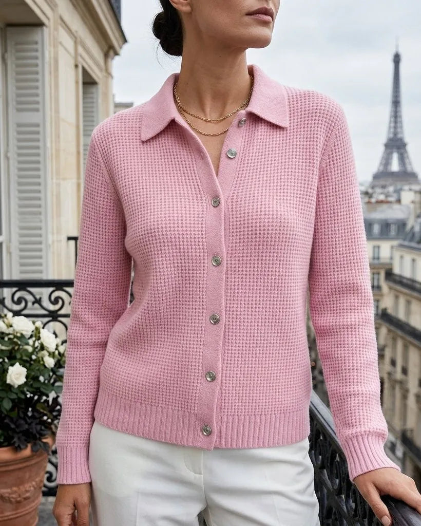 Woman wearing a soft pink ribbed knit cardigan with collar and button front, standing near roses on a balcony