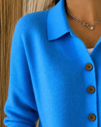 Detail shot of the blue cardigan's collar and top three wooden buttons against the ribbed knit texture