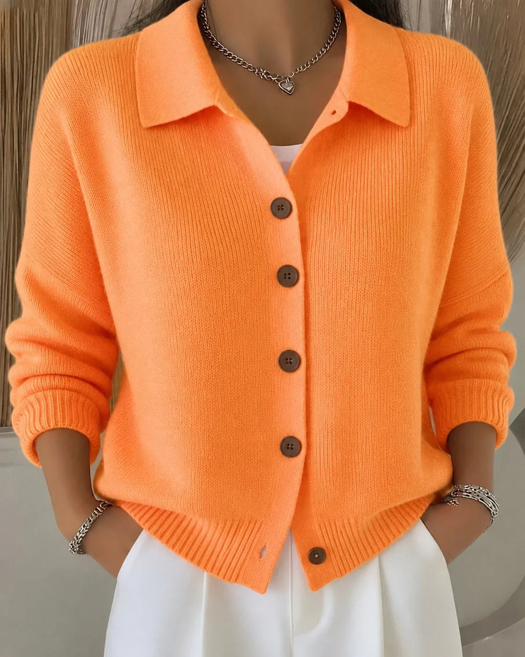 Front view of an orange ribbed knit cardigan with a polo collar, long sleeves and brown wooden buttons down the front