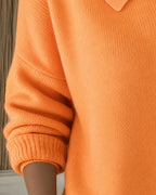 Close-up of the orange cardigan's sleeve and ribbed cuff, highlighting the soft knit texture and relaxed fit