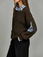 Side profile showing the dark brown knit jumper's dropped shoulder and cut-out sleeve revealing the striped shirt underneath