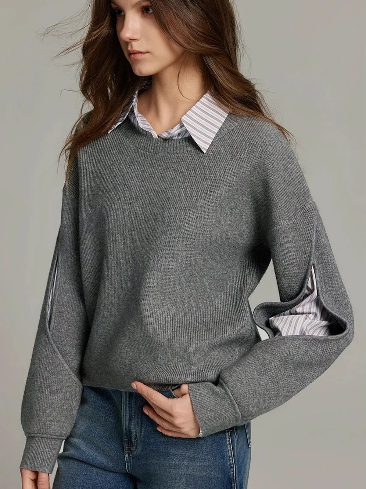 Grey ribbed knit jumper worn over a striped shirt, front view with hand resting at the waist