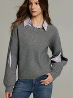 Grey knit jumper close-up showing the cut-out sleeve detail with the striped shirt visible underneath