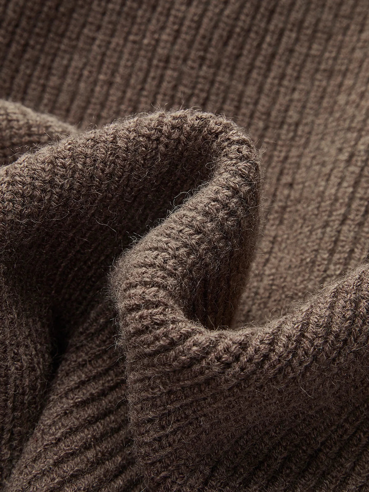 Close-up of the dark brown ribbed cuff and fabric folds highlighting the knit's soft, textured finish