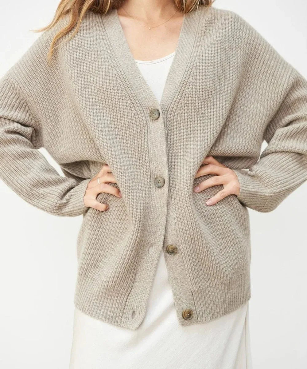 Close-up of beige ribbed cardigan showing V-neck, button placket and relaxed fit against hip