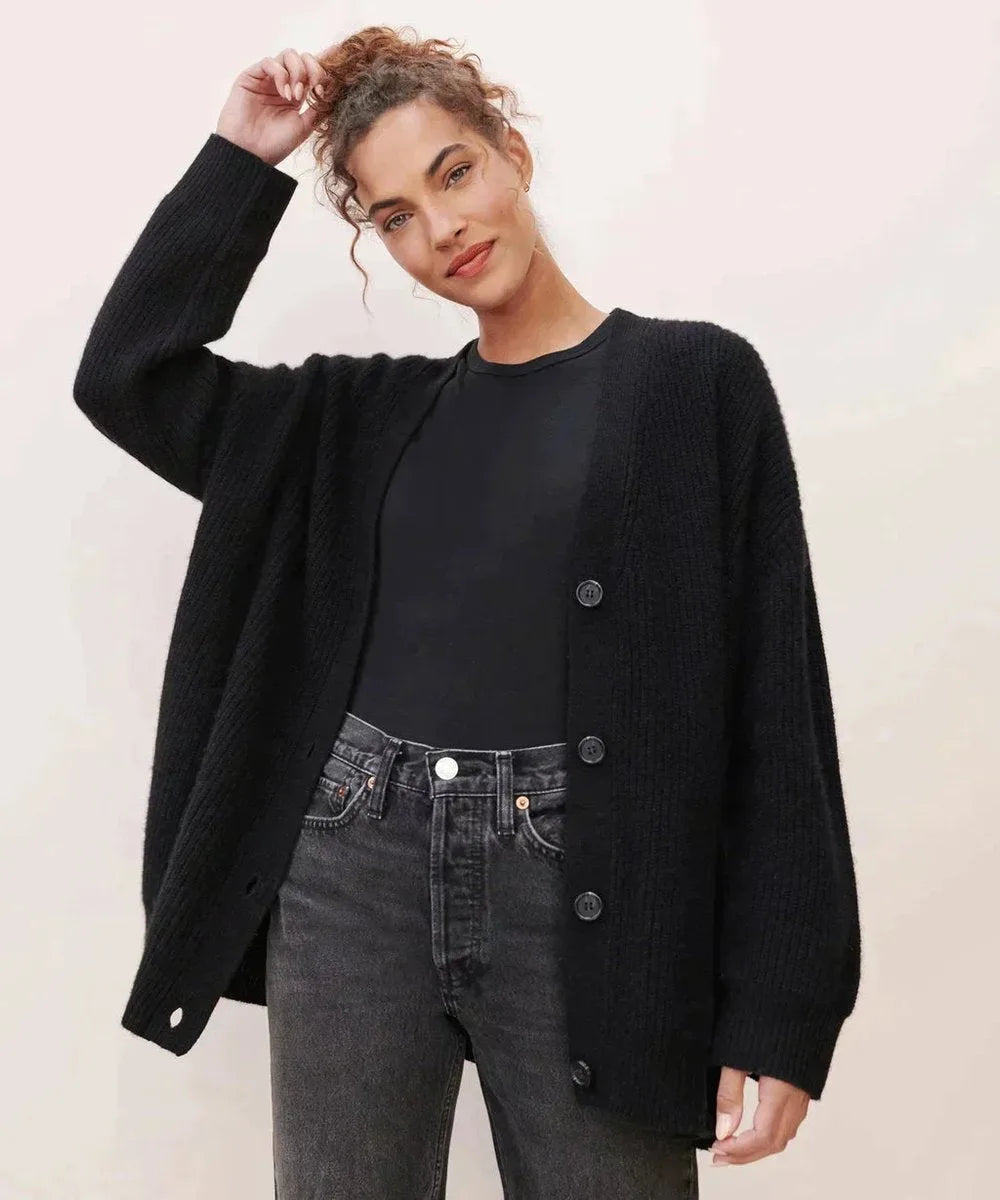 Front view of black ribbed cardigan buttoned over a black top, paired with dark washed jeans