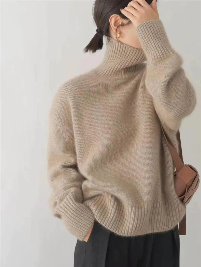 Back view of a khaki polo neck jumper paired with a tan crossbody bag and dark trousers