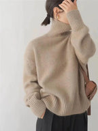 Back view of a khaki polo neck jumper paired with a tan crossbody bag and dark trousers