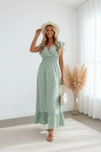 Front view of the sage green maxi dress showing the V-neckline, ruffle sleeves and ditsy print in a bright indoor setting