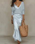 Pale blue satin slip skirt paired with a matching light blue ribbed jumper, walking pose with a straw tote bag