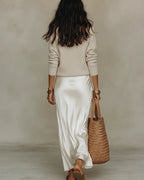 Ivory satin slip dress with thin straps and a V-neckline shown without the jumper, revealing the sleek satin fabric