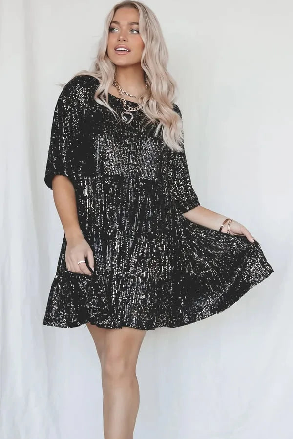 Black sequin tiered mini dress with three-quarter sleeves shown from the front, model holding the skirt to reveal the flared shape