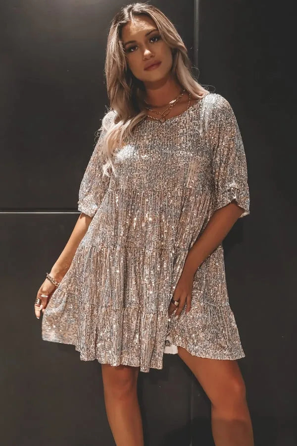 Silver sequin tiered mini dress against a dark background, showing the loose oversized fit and dropped shoulder sleeves