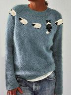 Front view of dusty blue knitted jumper showing sheep and sheepdog motif knitted above the ribbed crew neckline
