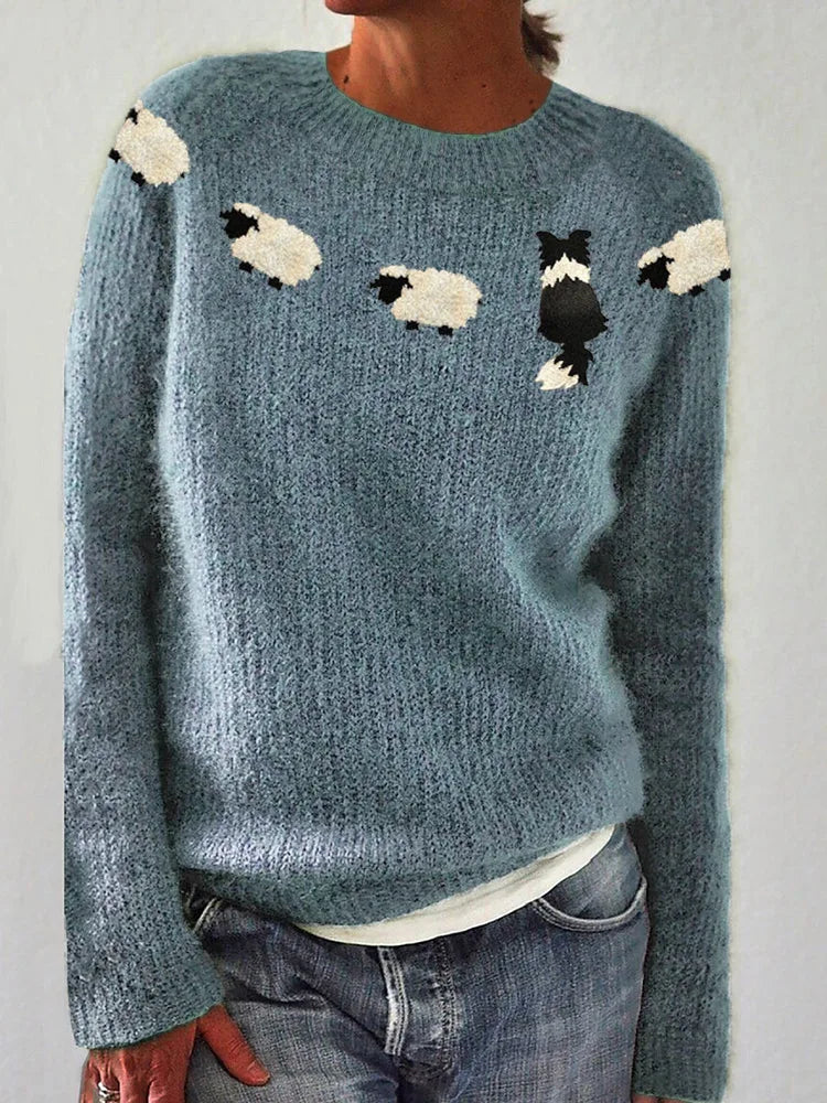Front view of dusty blue knitted jumper showing sheep and sheepdog motif knitted above the ribbed crew neckline