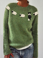 Front view of sage green knitted jumper with cream sheep and black sheepdog pattern paired with denim jeans