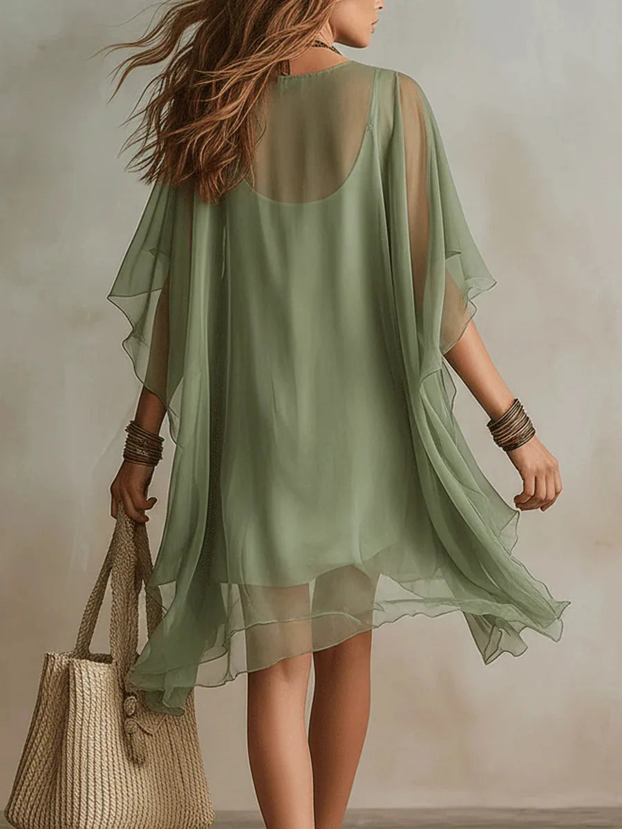 Back view of the sheer green tunic dress showing the open shoulder cut-outs and draped chiffon fabric
