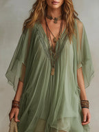 Detail shot of the V-neckline embroidery and sheer fluttering sleeves against layered gold necklaces