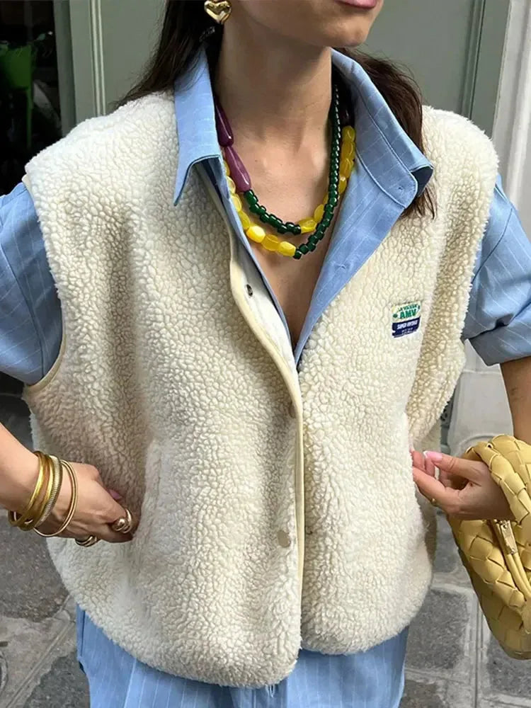 Close-up of the cream sherpa fleece body warmer collar and snap buttons worn over a striped shirt