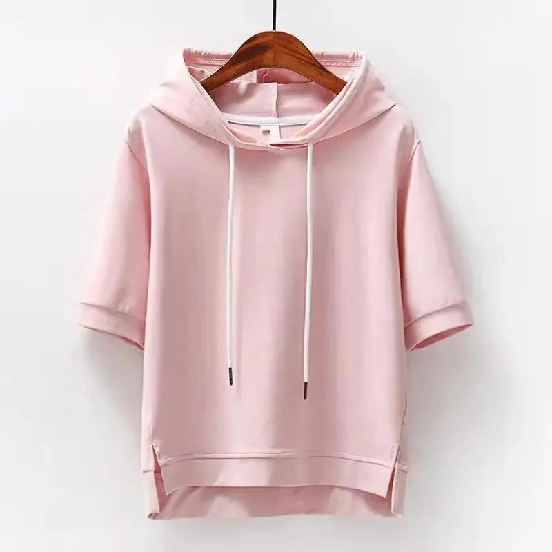 Pink short-sleeve drawstring hoodie on a wooden hanger, showing the relaxed hood and high-low hem