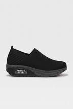Side profile of black knit slip-on trainer with chunky wedge sole and visible air-bubble cushioning unit