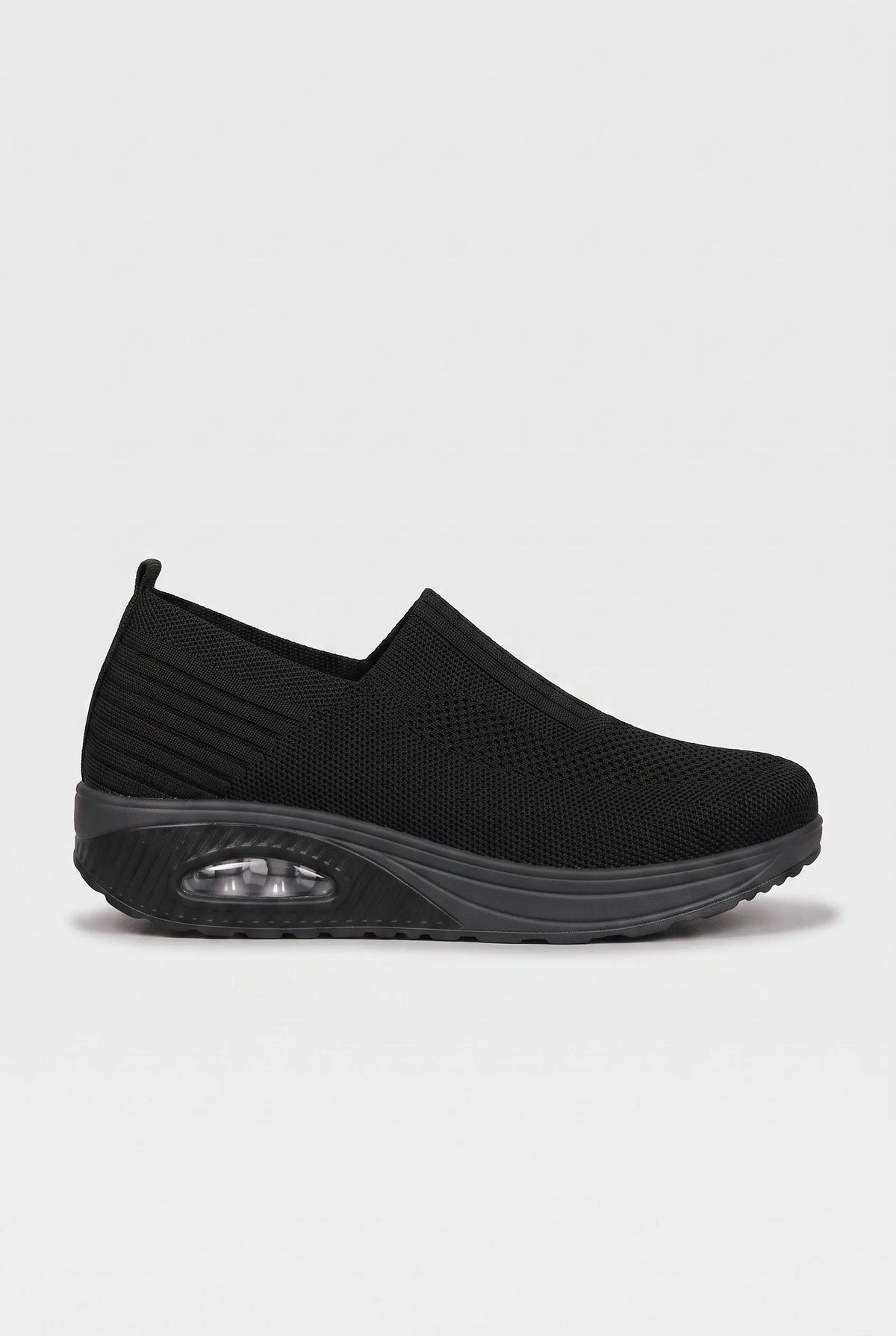 Side profile of black knit slip-on trainer with chunky wedge sole and visible air-bubble cushioning unit
