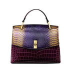 Front view of a structured shoulder bag with a purple snakeskin-effect flap and burgundy crocodile-effect body, gold hardware