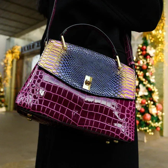 Woman carrying the purple and burgundy handbag on her shoulder outdoors near festive lights