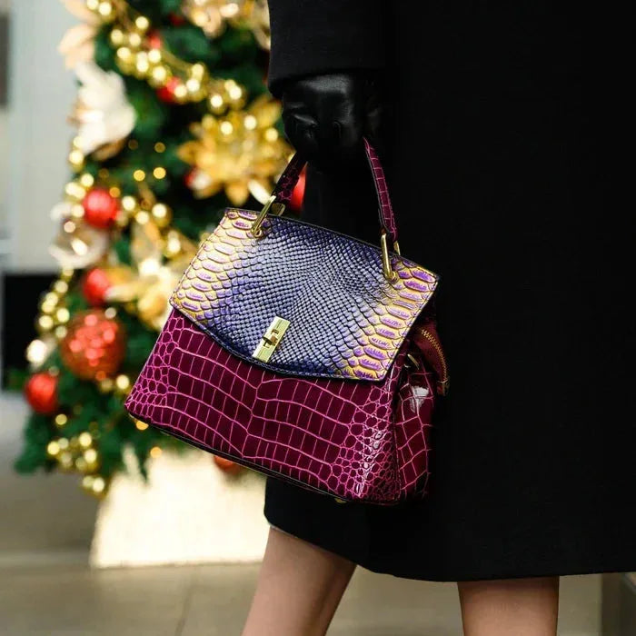 Woman holding the purple and burgundy bag by its top handle against a black outfit outdoors