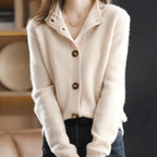 Close view of a cream cashmere cardigan with notched collar, V-neck and brown buttons worn open at the neckline