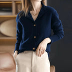 Navy cashmere cardigan with notched lapel collar and brown buttons, worn with cream trousers and layered necklace