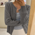 Grey knitted cardigan with round neckline and button front, worn open over a ribbed camisole