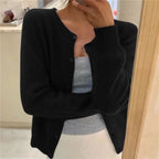 Black button-front cardigan with round neckline shown close up, styled over a grey camisole