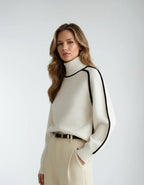 Three-quarter view of the cream knit jumper showing its relaxed drop-shoulder fit and ribbed cuff