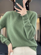 Close-up of soft sage green knit jumper with ribbed round neckline and relaxed long sleeves