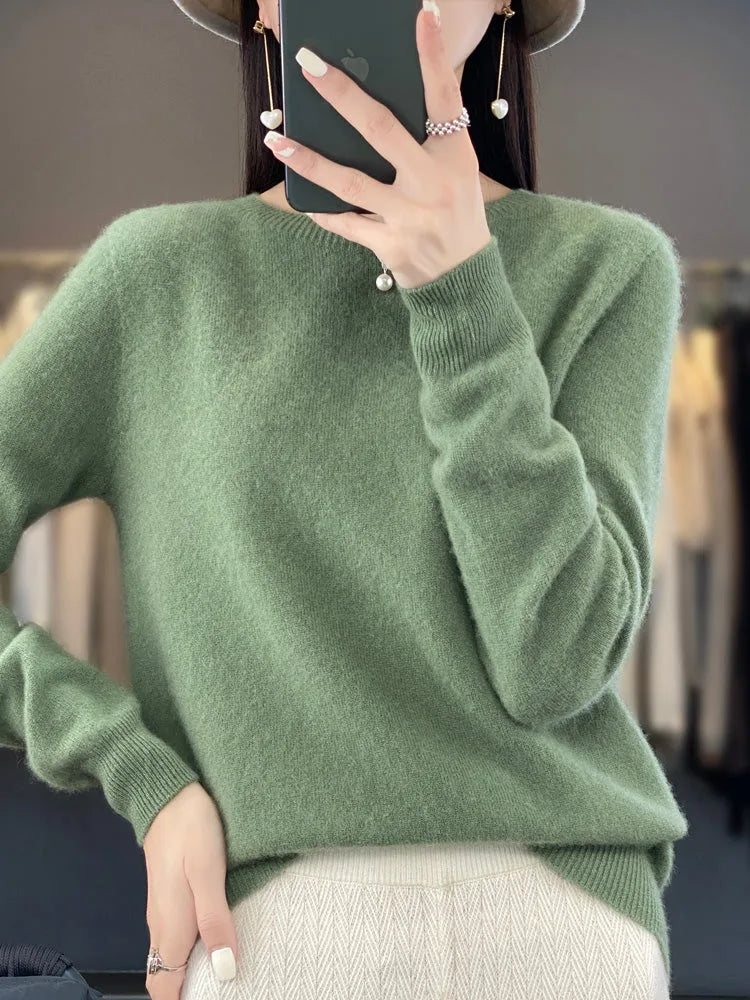 Close-up of soft sage green knit jumper with ribbed round neckline and relaxed long sleeves